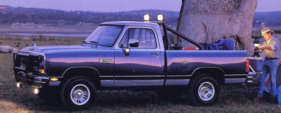 A 1990 Dodge Ram D150 pickup truck with two-tone paint, parked in front of a construction site.