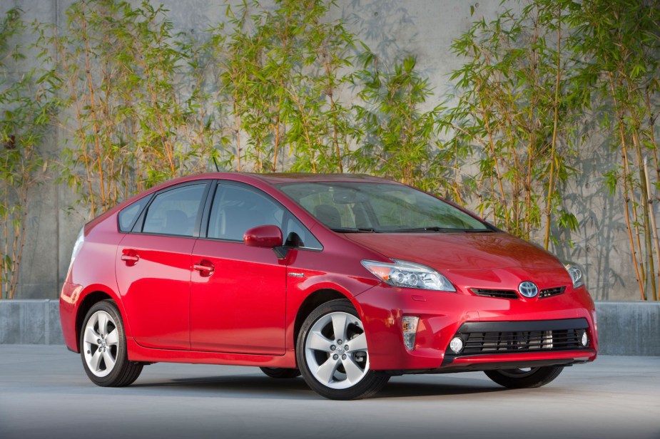 Toyota Prius hybrid sedan parked on concrete, bamboo plants visible in the background.