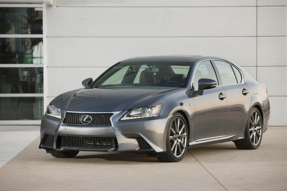 A midsize luxury Lexus GS sedan parked in front of a garage, in a driveway.