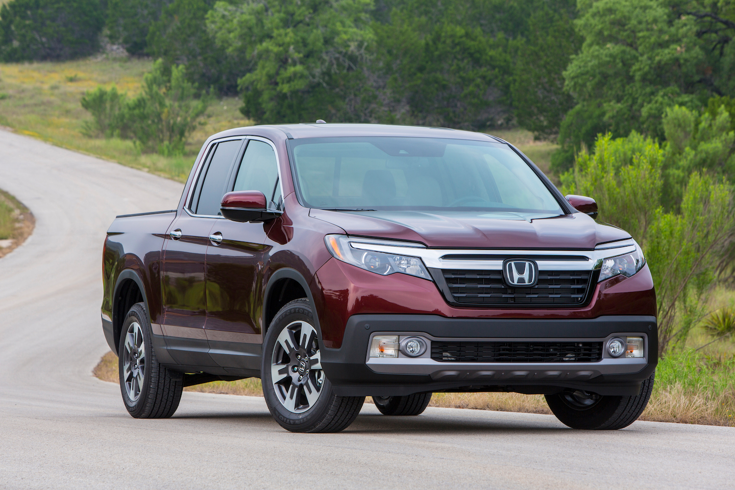 Maroon Honda Ridgeline unibody compact pickup truck parked on a paved road.