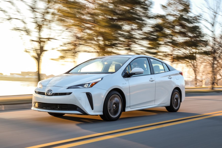 A white 2019 Toyota Prius driving, the Toyota Prius is a used car with a high price