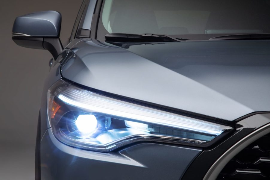 The headlight of a silver 2022 Toyota Corolla Cross a Toyota SUV with the best gas mileage.