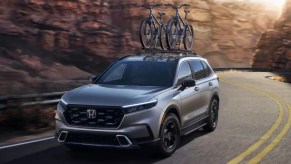 A gray 2023 Honda CR-V small SUV is driving on the road.