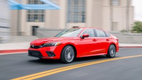 A red 2023 Honda Civic Sedan driving around a bend