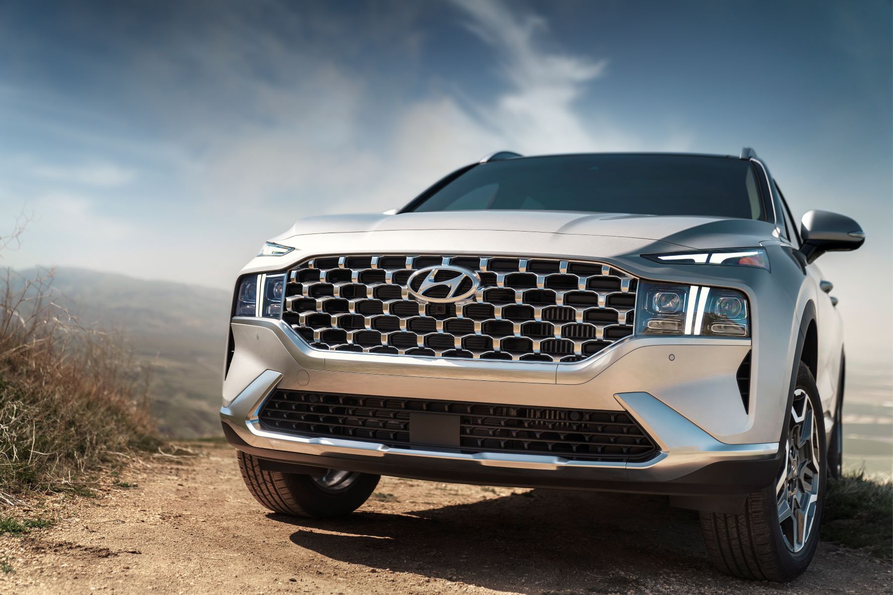 A closeup of the grille of a 2023 Hyundai Santa Fe Plug-in Hybrid midsize SUV model parked on a dirt trail