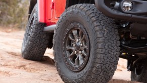 Closeup of the oversized tires on a Jeep Wrangler Rubicon 392 American SUV, while they navigate an off-road 4x4 trail.