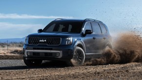 A blue 2023 Kia Telluride midsize SUV is driving off-road.