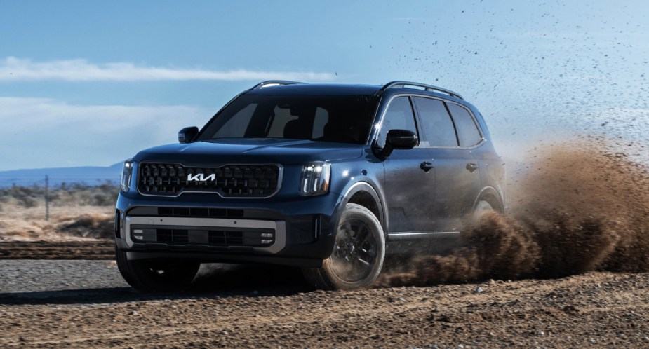 A blue 2023 Kia Telluride midsize SUV is driving off-road. 