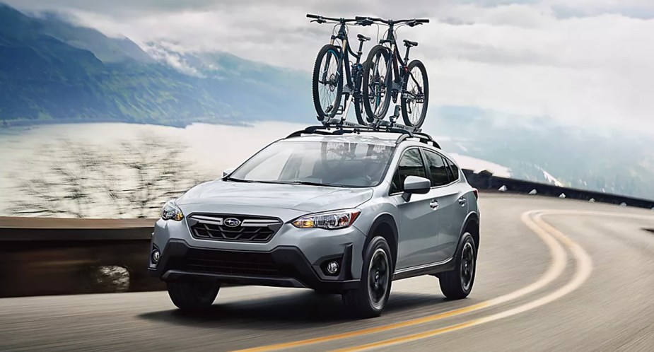 A blue 2023 Subaru Crosstrek subcompact SUV is driving on the road. 