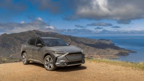 A grey 2023 Subaru Solterra parked in front of a body of water.