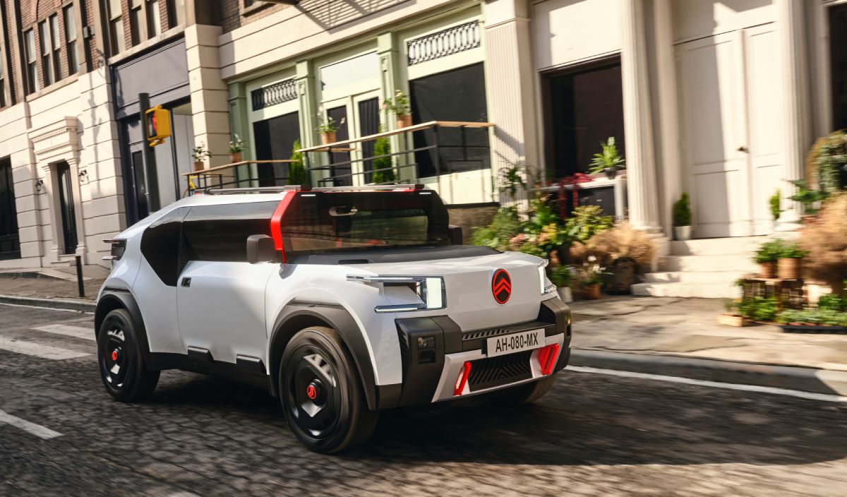 A white Citroen OLI electric vehicle driving down a city street.