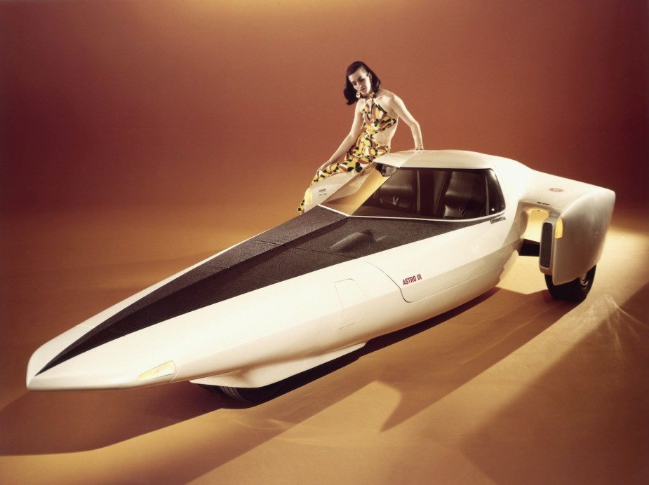 A model leans against a futuristic Chevrolet Astro prototype on stage at an auto show in 1969.