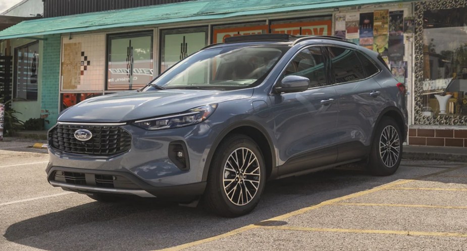 A gray 2023 Ford Escape is parked outside of a shop. 