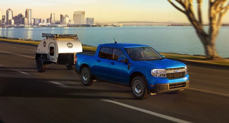 A blue Ford Maverick small pickup truck is driving on the road. MotorTrend likes this compact vehicle.