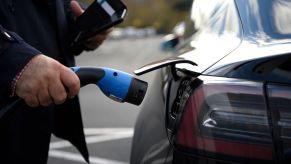 A Tesla owner plugs a free EV charge cable into the port of their EV sedan.