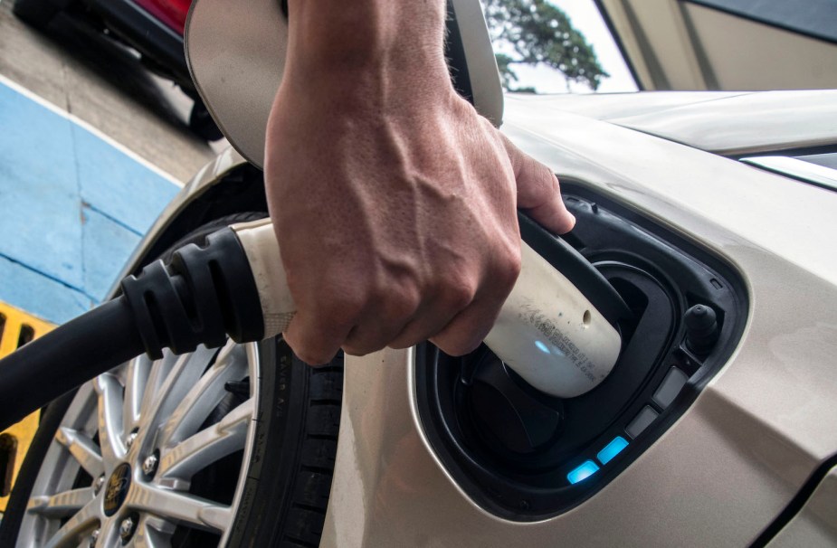 Closeup of the hand of Ford EV driver plugging in a cable to charge up their vehicle's battery.