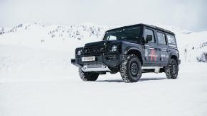 The grille of an Ineos Grenadier 4x4 SUV, a snowy mountain range in the background.