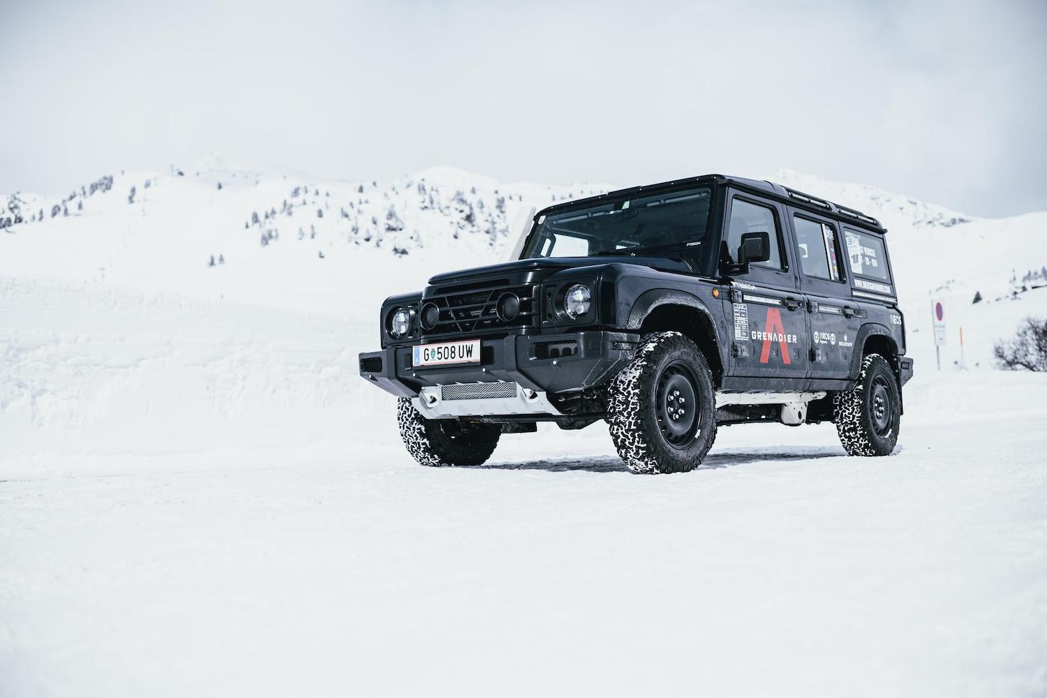 The grille of an Ineos Grenadier 4x4 SUV, a snowy mountain range in the background.