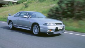 An R33 Nissan GT-R Skyline drives down a road.