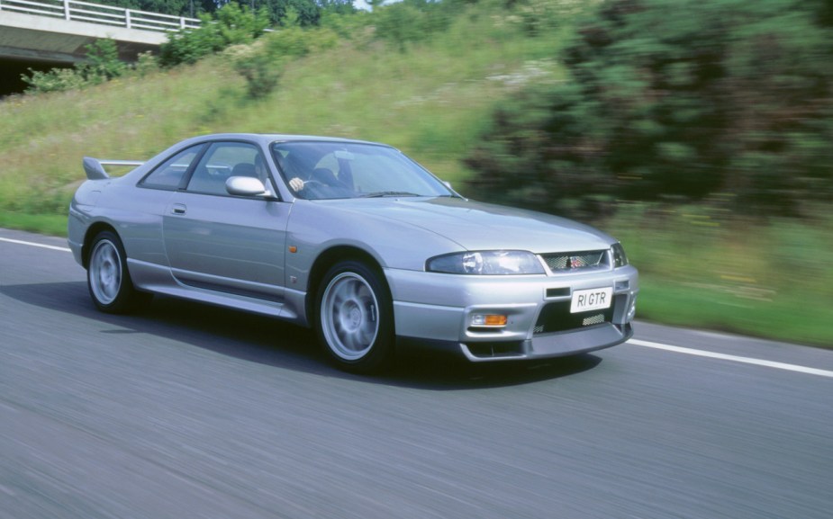 An R33 Nissan GT-R Skyline drives down a road.