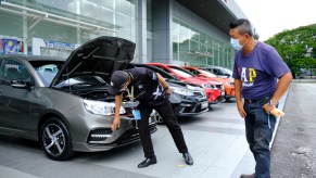 A person inspecting a vehicle at a car dealership, potentially with an unfixable defect.