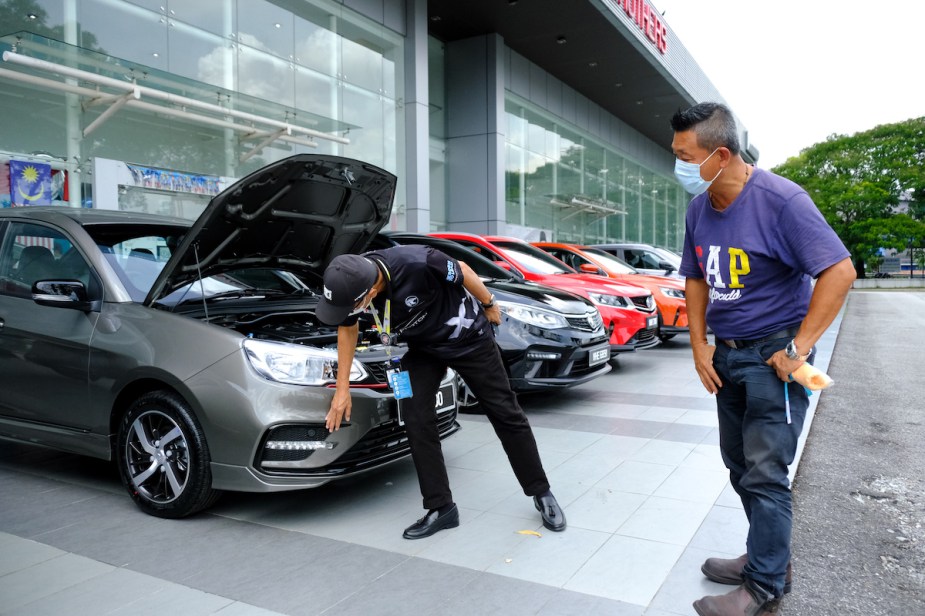 A person inspecting a vehicle at a car dealership, potentially with an unfixable defect.  