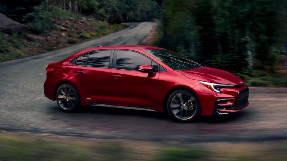 Red 2023 Toyota Corolla compact car driving on a curvy road