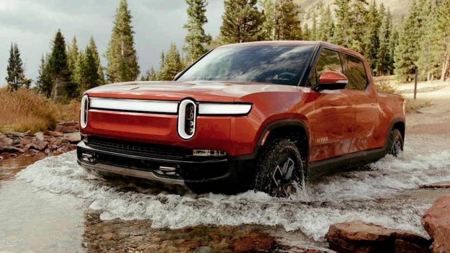 Red Rivian R1T Fording Through Deep Water