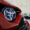 A Toyota logo on a red Toyota Camry, which is one of the least expensive cars to maintain.