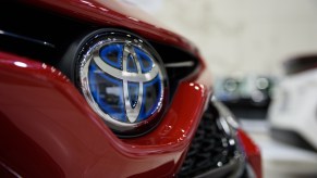 A Toyota logo on a red Toyota Camry, which is one of the least expensive cars to maintain.