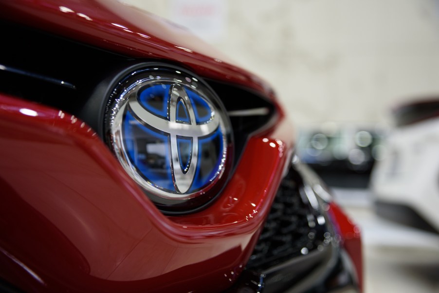 A Toyota logo on a red Toyota Camry, which is one of the least expensive cars to maintain.