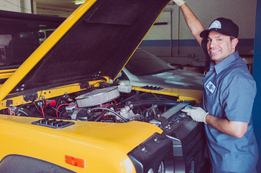 A man performing scheduled vehicle maintenance on a car