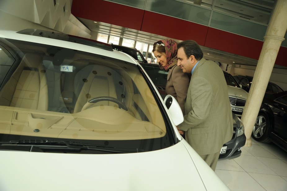 A couple looks at a brand new Porsche Cayenne in a car showroom.