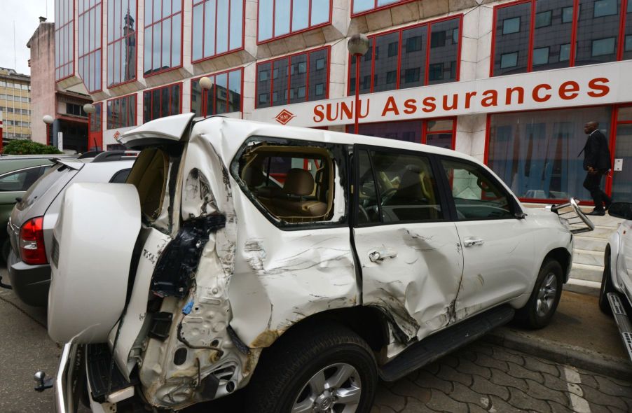 A damaged SUV parked in front of a SUNU Assurances insurance group office in Abidjan