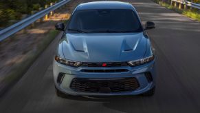 A blue-gray 2023 Dodge Hornet plug-in hybrid electric vehicle (PHEV) driving down a highway