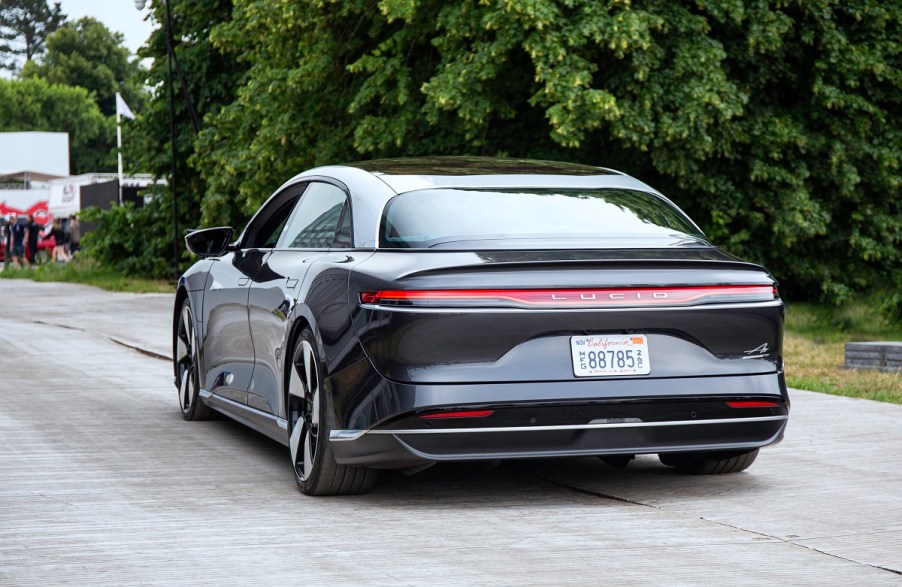 A Lucid Air electric car is shown on a paved road from the rear view.