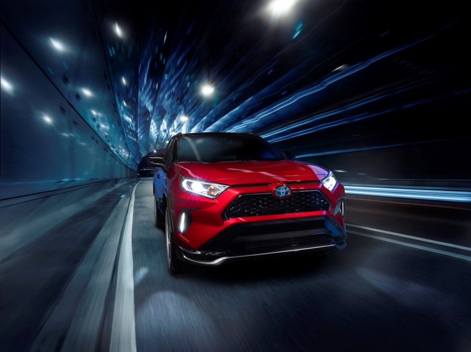 A red Toyota RAV4 Prime plug-in hybrid electric vehicle (PHEV) driving through a lighted tunnel