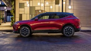 A side profile shot of a red 2023 Chevrolet Blazer RS midsize SUV parked on a cobblestone crosswalk