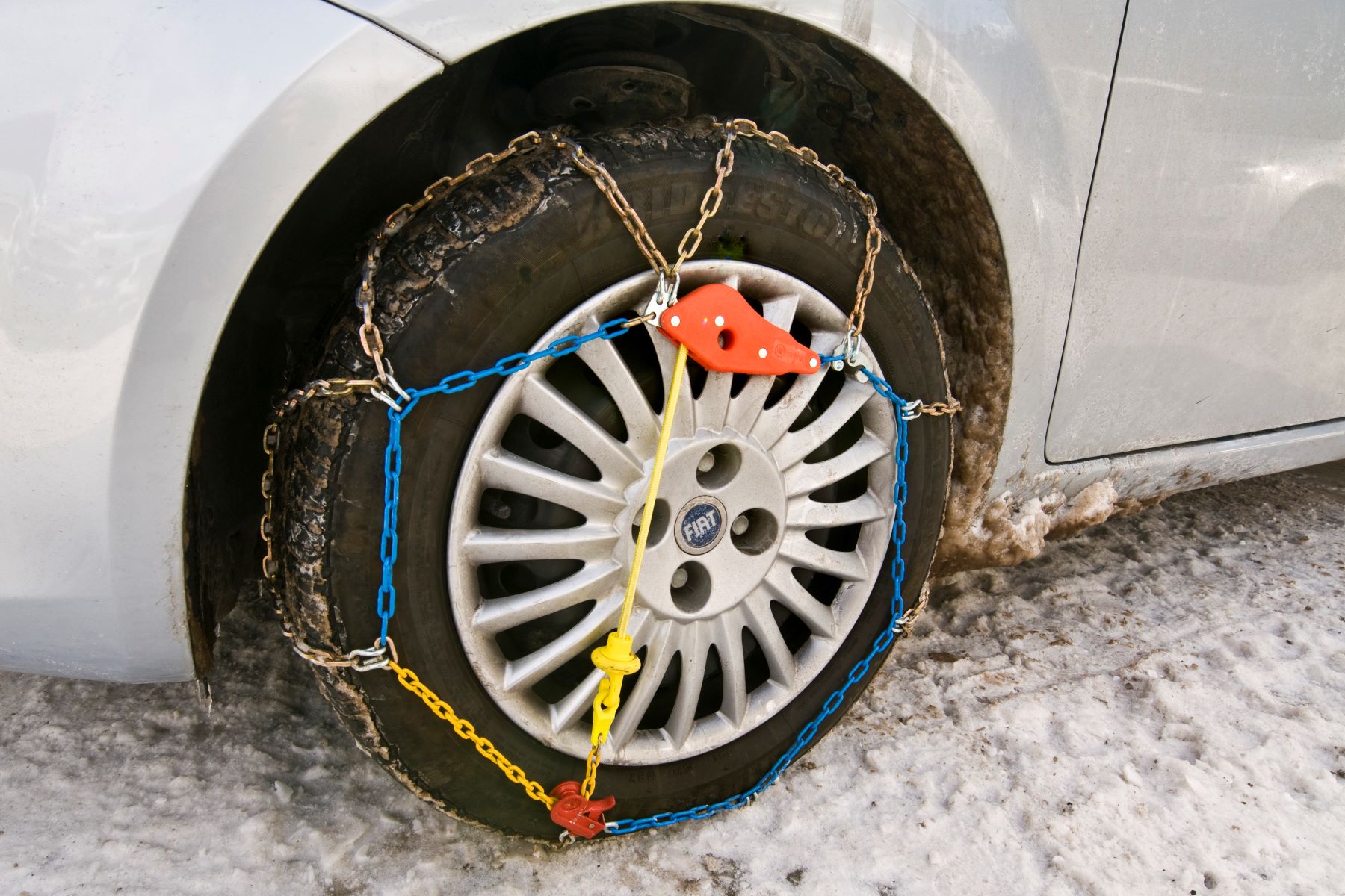 A Fiat car with a tire chain attached for winter and snowy weather driving conditions