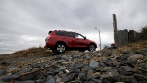 A red Toyota RAV4 is shown climbing a rocky hill