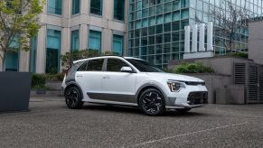 A white 2023 Kia Niro EV parked on a rooftop and surrounded by skyscrapers in an urban city area