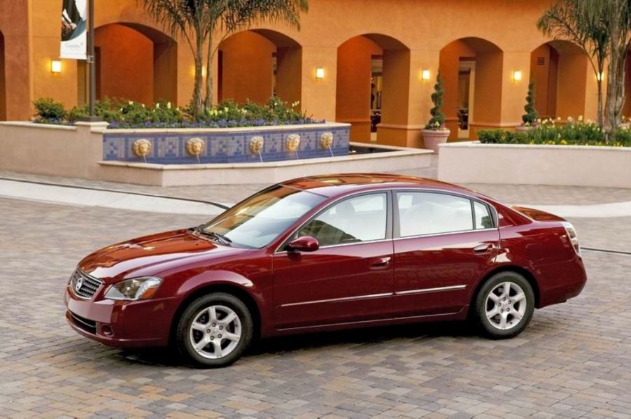 A dark red 2006 Nissan Altima midsize sedan model parked on a cobblestone villa