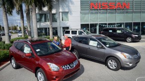 A pair of 2013 Nissan Rogue SUVs sit at a dealership, it might be a good used SUV.