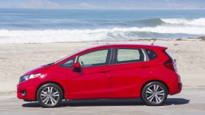 A Honda Fit hatchback in red poses by the beach.