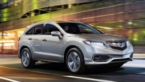 A gray 2018 Acura RDX small luxury SUV is driving on the road.