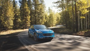 A 2022 Ford Escape PHEV driving down a wooded area.