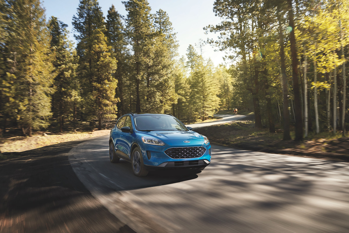 A 2022 Ford Escape PHEV driving down a wooded area.