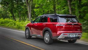 A 2022 Nissan Pathfinder driving down a wooded road.