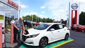 White Nissan Leaf EV parked at a dealership, charging.