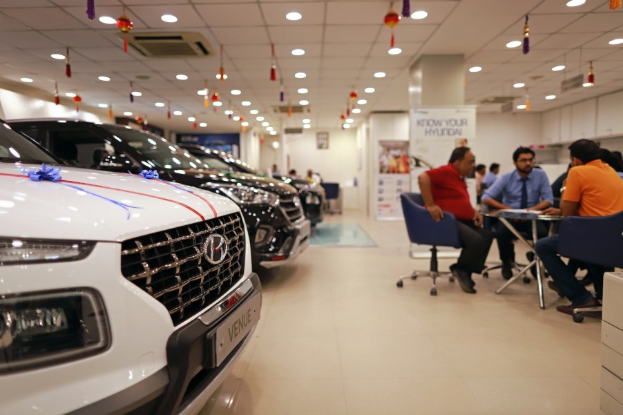 A row of Hyundai EVs parked inside a dealership, a table of customers speak with a salesperson in the background.